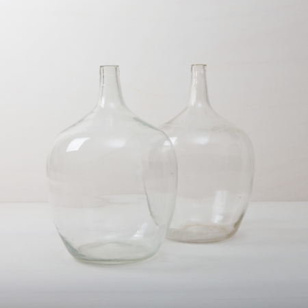 Demijohn Arenal Clear XL | How many liters of wine may have been made in these demijohn for roaring celebrations? That will probably forever remain a mystery. It is quite clear, however, that these demijohn are a wonderful decoration for your celebration today. Whether alone or as a group, the beautiful, bulbous shapes and different shades of green make them a real feast for the eyes. They are ideal as vases for long grasses or exotic single flowers.The demijohn are available in different sizes. Some are small enough to fit on the table, others are more suitable for decoration on the floor. | gotvintage Rental & Event Design