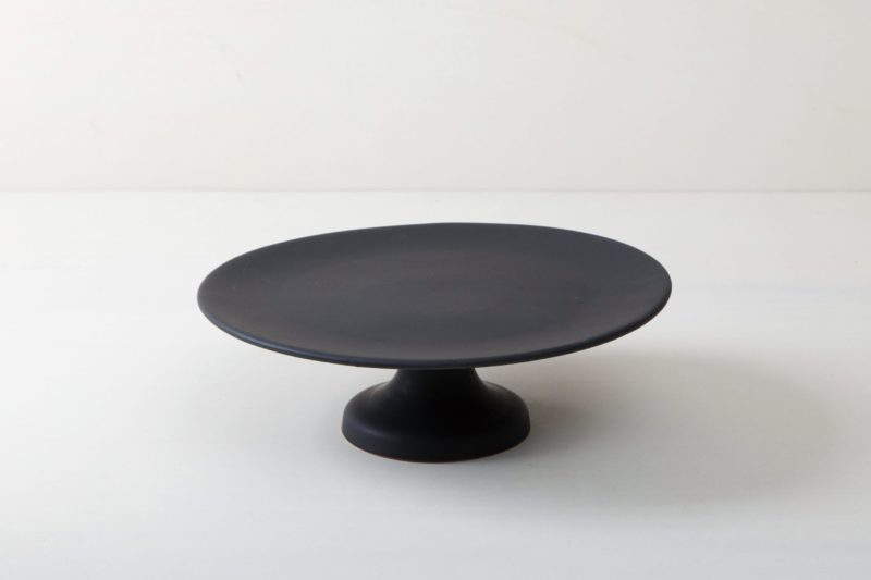  | Our medium size elevated cake stand Ernesta rests on a 13 cm high foot and has a diameter of 35 cm. On the matt black serving tray there is enough room to present and arrange cakes, cupcakes, sushi and other delicacies on the table or at the modern buffet. The serving trays are handcrafted from high-quality terracotta and glazed matt black, obviously food safe.These cake stands are available in three different sizes as well as a matt white serving tray. They can be wonderfully combined for p... | 