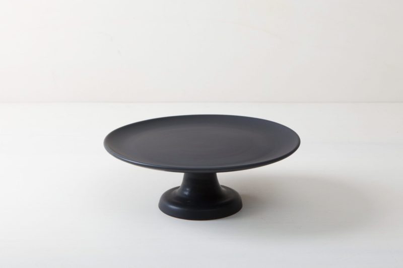  | Our small elevated round cake stand Ernesta rests on a 12 cm high foot and has a diameter of 32 cm. On the matt black serving tray there is space to present and arrange cakes, cupcakes, sushi and other delicacies on the table or at the modern buffet. The serving trays are handcrafted from high-quality terracotta and glazed matt black, obviously food safe.These cake stands are available in three different sizes as well as a matt white serving tray. They can be wonderfully combined for present... | 