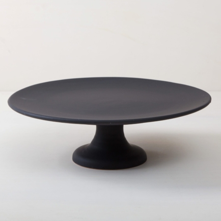 Cake Stand Ernesta Matt Black XL | Our large round elevated cake stand Ernesta rests on a 15 cm high foot and has a diameter of 40 cm. On the matt black serving tray there is enough space to present and arrange cakes, cupcakes, sushi and other delicious food on the table or at the modern buffet. The serving trays are handcrafted from high-quality terracotta and glazed matt black, obviously food safe.These cake stands are available in three different sizes as well as a matt white serving tray. They can be wonderfully combined for presentations. | gotvintage Rental & Event Design